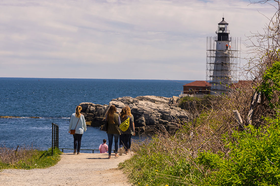 Girls walk by Portland Head Light scaffolding restoration, May 2016 [completed June, '16] - Photo by: Cindy Farr-Weinfeld
